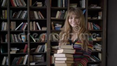 年轻漂亮的女孩拿着一叠书在书架前